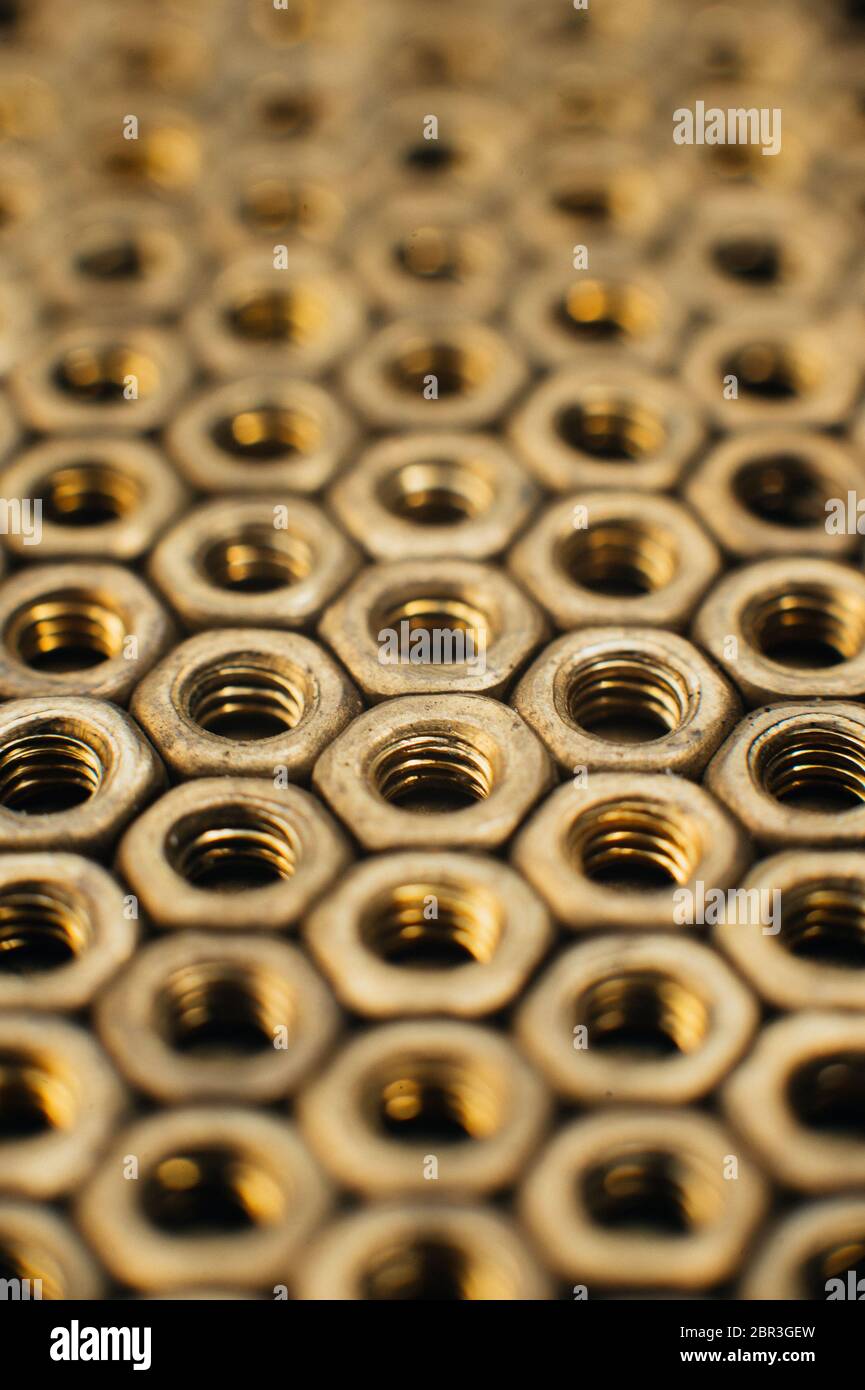 Primo piano, macro. Vecchi dadi di ottone sovietico. Struttura, fondo di noci di ottone disposte in forma di nido d'ape. Dadi di colore oro. Dadi sporchi nell'olio. B Foto Stock