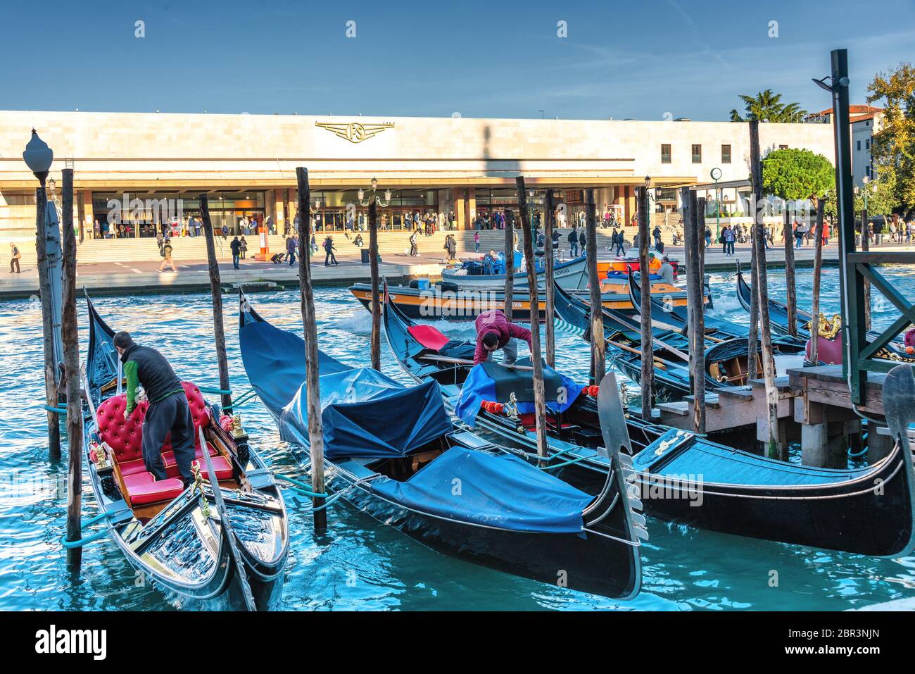 Immagine simbolica di Venezia: Le gondole ormeggiate tra i pali del Canal Grande, di fronte alla stazione ferroviaria di Santa Lucia Foto Stock