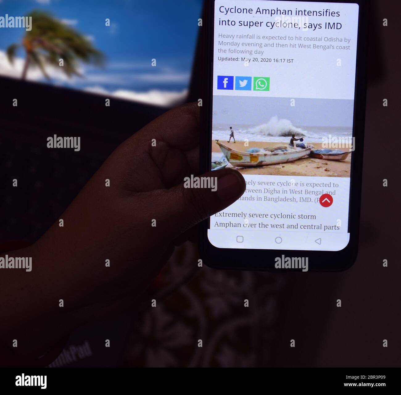 Una signora indiana che naviga e guarda le notizie di disastro del ciclone di Amphan sul suo cellulare. Foto Stock