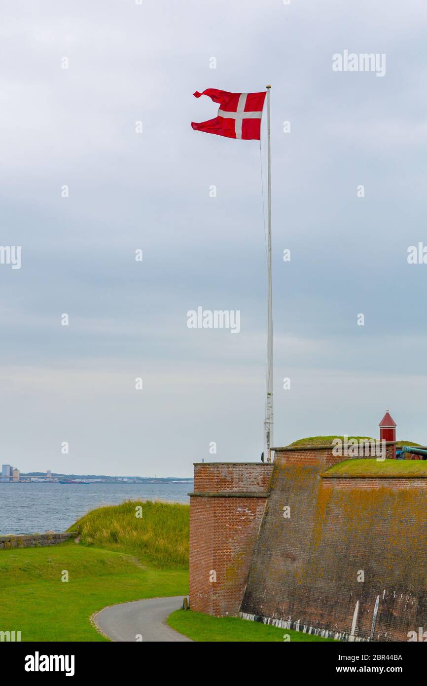 Bandiera danese vicino al castello di Kronborg in Danimarca. Bandiera danese vicino al famoso castello di Kronborg sulla costa del mare. Porto danese di Helsingor con Kro Foto Stock
