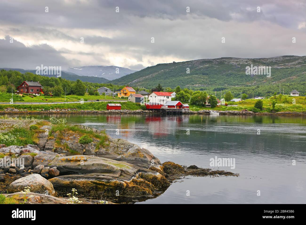 Splendido paesaggio con le acque bordo, villaggio, chiesa e montagne sullo sfondo, Saltstraumen, comune di Bodo, contea Nordland, Norvegia. Foto Stock