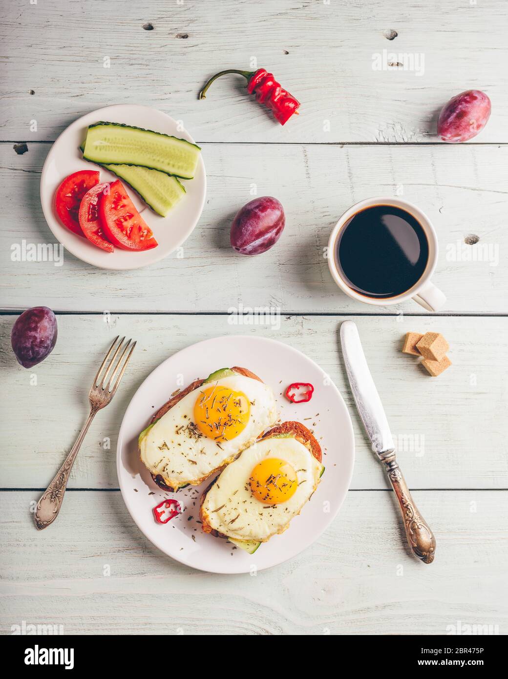 La colazione brinda con verdure e uova fritte su piastra bianca, una tazza di caffè e un po' di frutta su sfondo di legno. Pulire a mangiare cibo concetto. Visualizza f Foto Stock