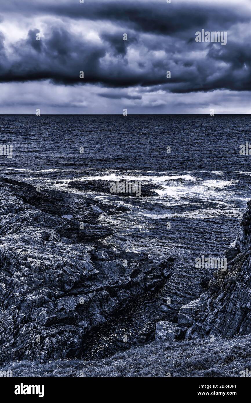 Alla scogliera rocciosa di notte. Onde bruciano contro la costa rocciosa. Foto Stock