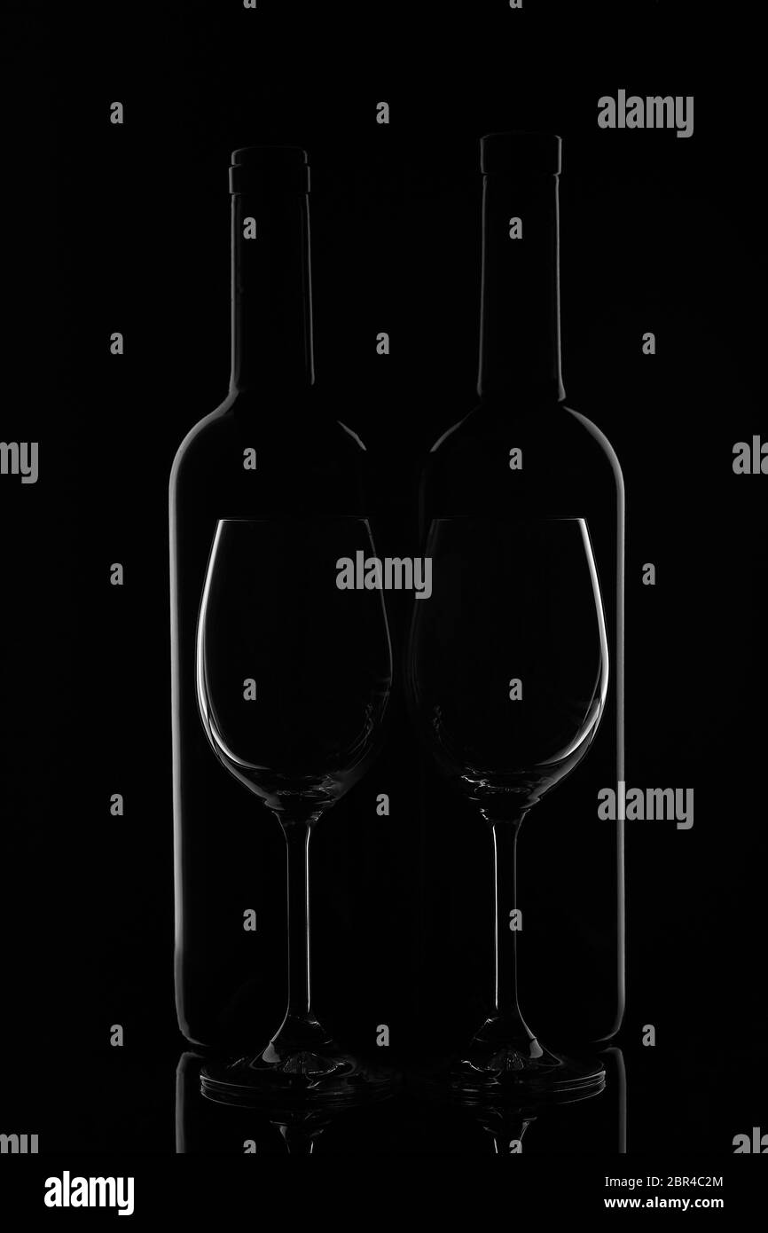 Silhouette di due bottiglie di vino e due verricelli vuoti su fondo nero con riflessi. Contorno con gradiente e evidenziazioni Foto Stock