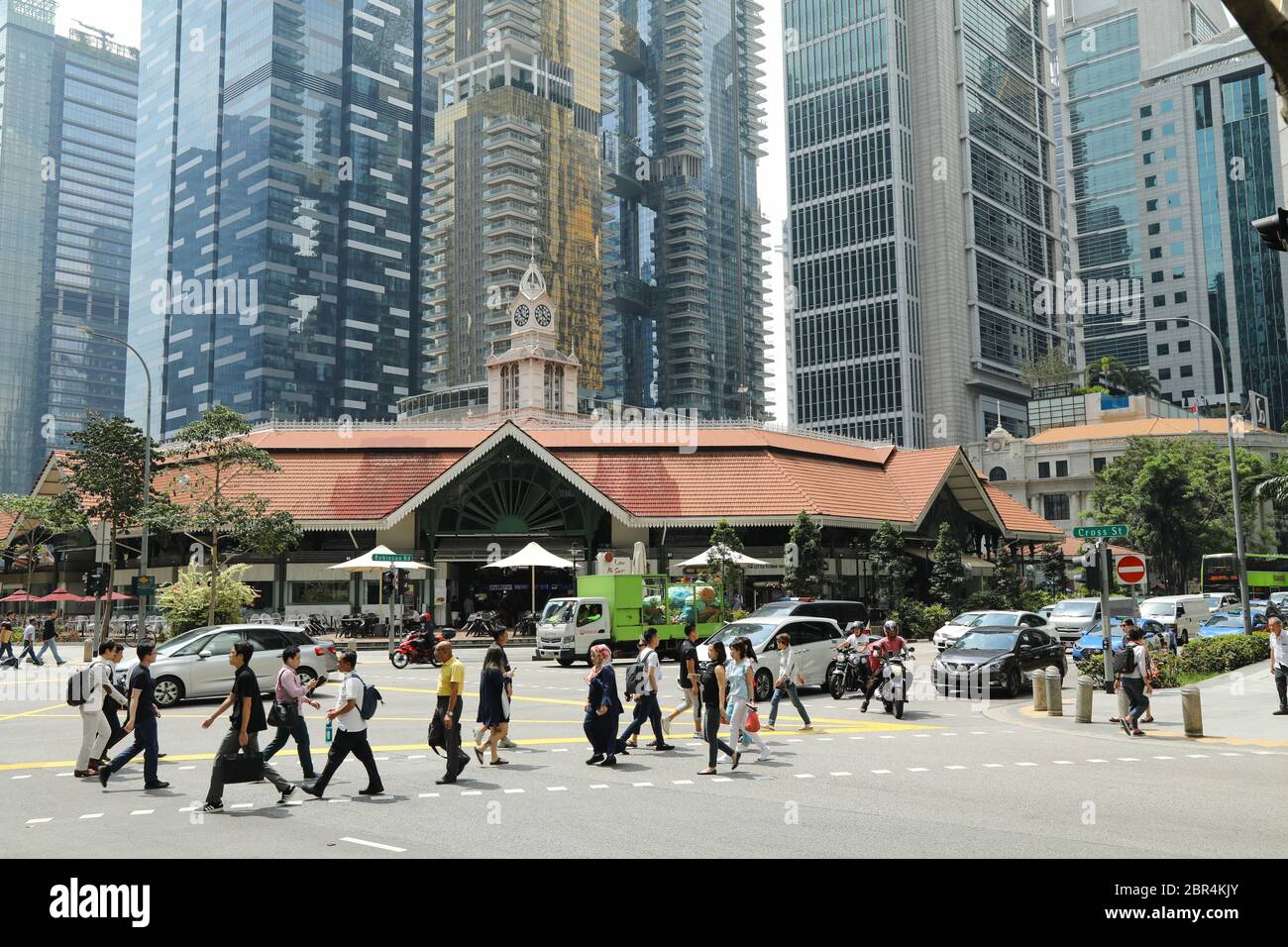 Pedoni che attraversano una strada trafficata nel quartiere centrale degli affari di Singapore. Foto Stock