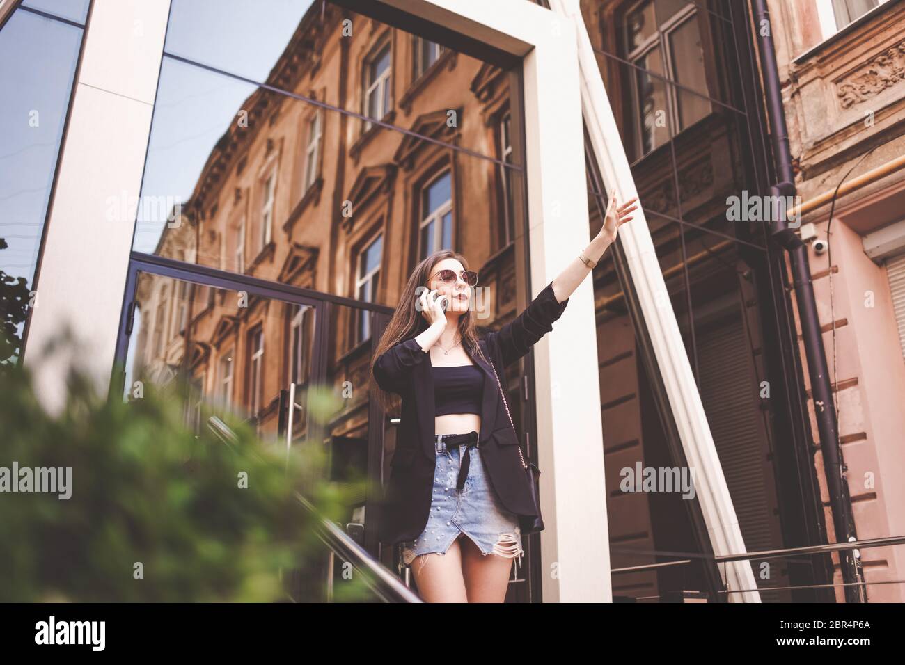 Bella ragazza che ondeggiava. Giovane donna di stile che parla al telefono e ferma un taxi Foto Stock