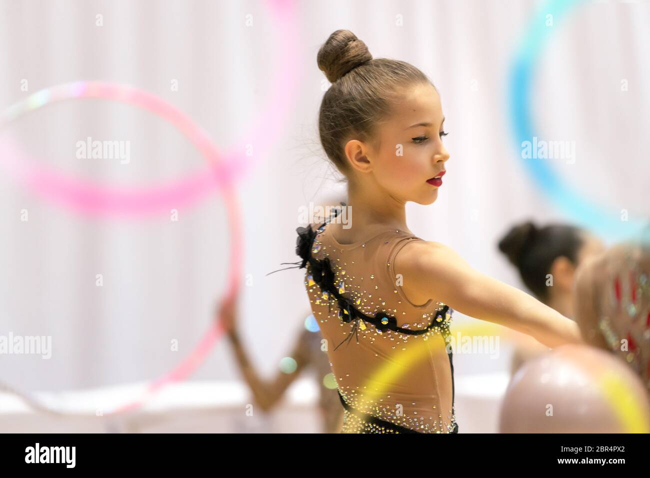 Piccola e bella ragazza ginnasta esegue una danza con un cerchio, sano ed attivo infanzia, sport, prendendo parte a una ginnastica ritmica della concorrenza Foto Stock