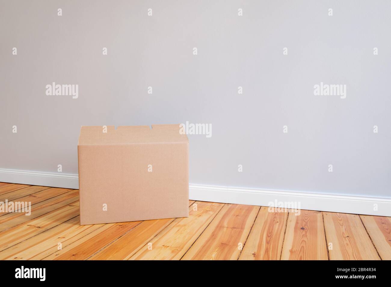 scatola di cartone su pavimento di legno in camera vuota, concetto di rilocazione Foto Stock