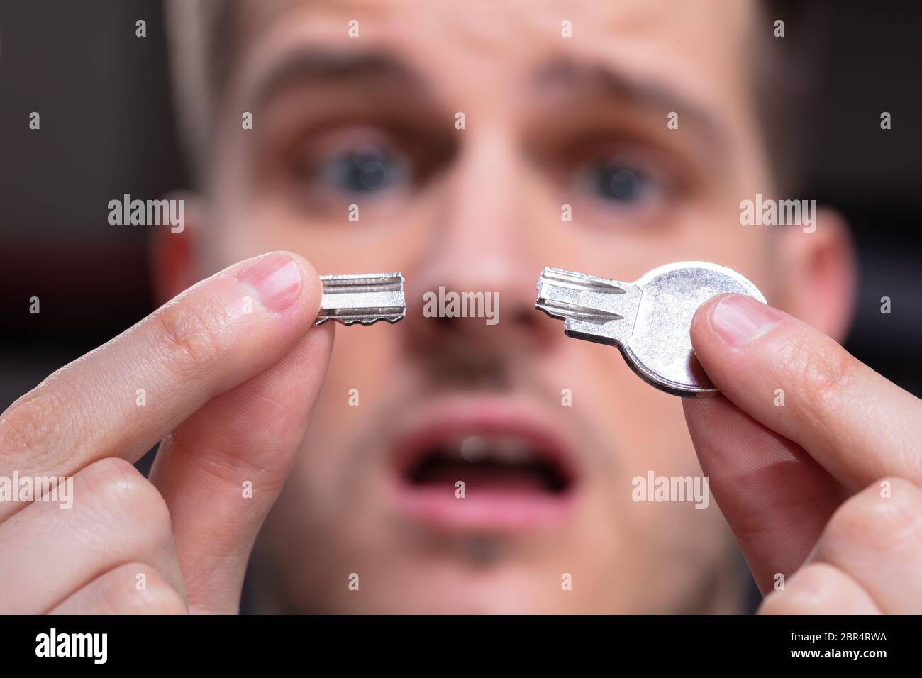 Ritratto di scioccato Man 's mano azienda argento chiave rotto Foto Stock