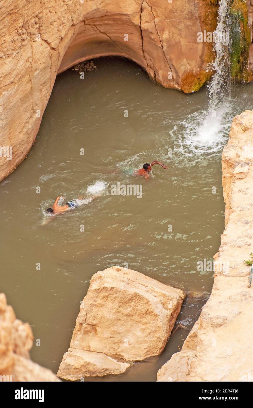 SAHARA, TUNISIA - 01 MAGGIO 2008: Due giovani nuotano in acqua in una stretta gola nel Sahara settentrionale Foto Stock