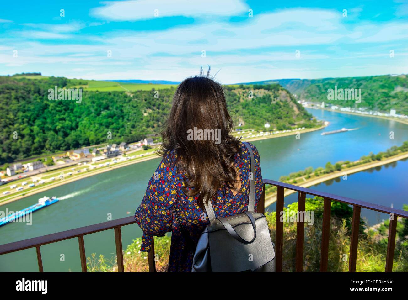 Bussines donna si appoggia sulla recinzione godendo la vista di un abisso sopra il fiume Foto Stock
