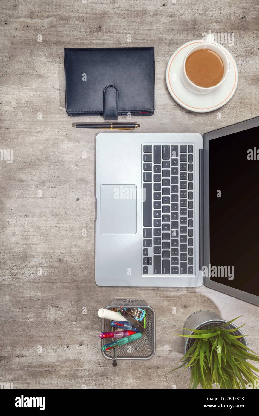 Vista superiore del banco affari con computer portatile, caffè, pianta in vaso, notebook e accessori business per l'ufficio Foto Stock