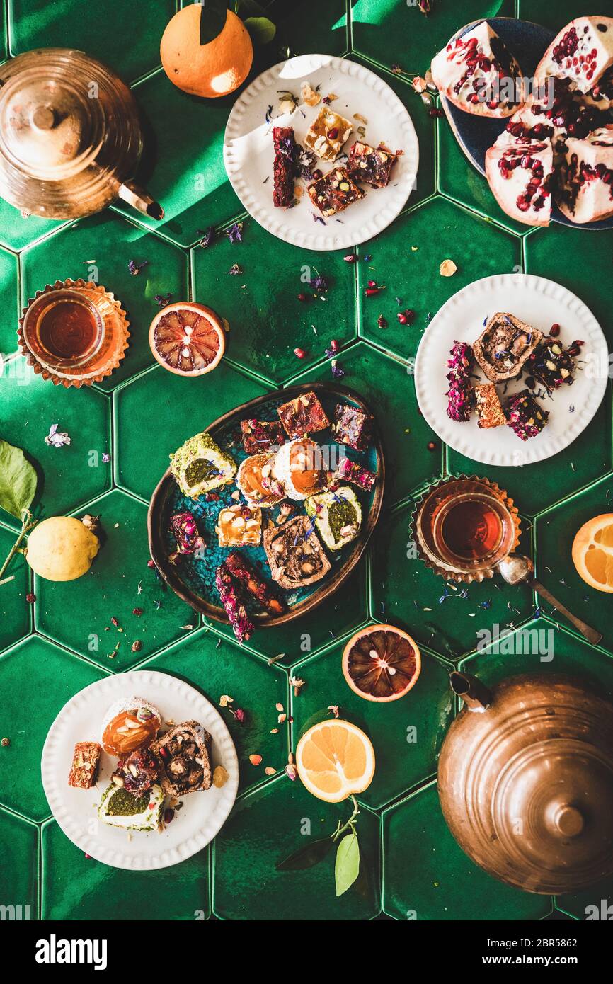 Piatto-lay di varietà di tradizionale turco lokum dolce delizia con tè turco in pentole di rame e tulipano bicchieri su verde marocchino piastrelle tavolo, top v Foto Stock