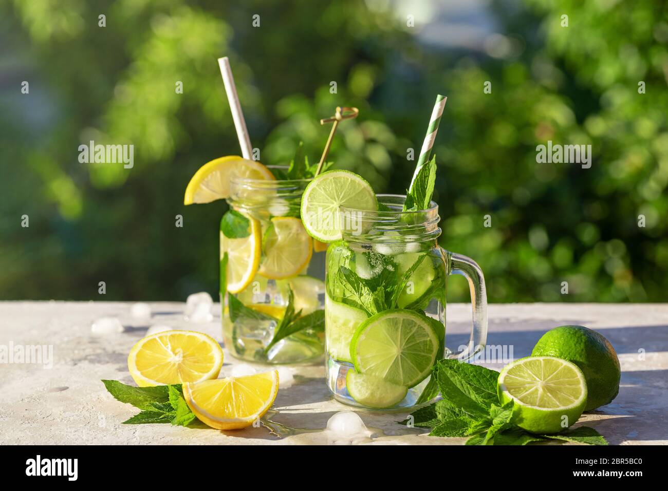 Due bicchieri di limonata o mojito cocktail con limone, cetriolo e menta, bevanda rinfrescante fredda o bevanda con ghiaccio e paglia di carta, all'aperto. Estate Foto Stock