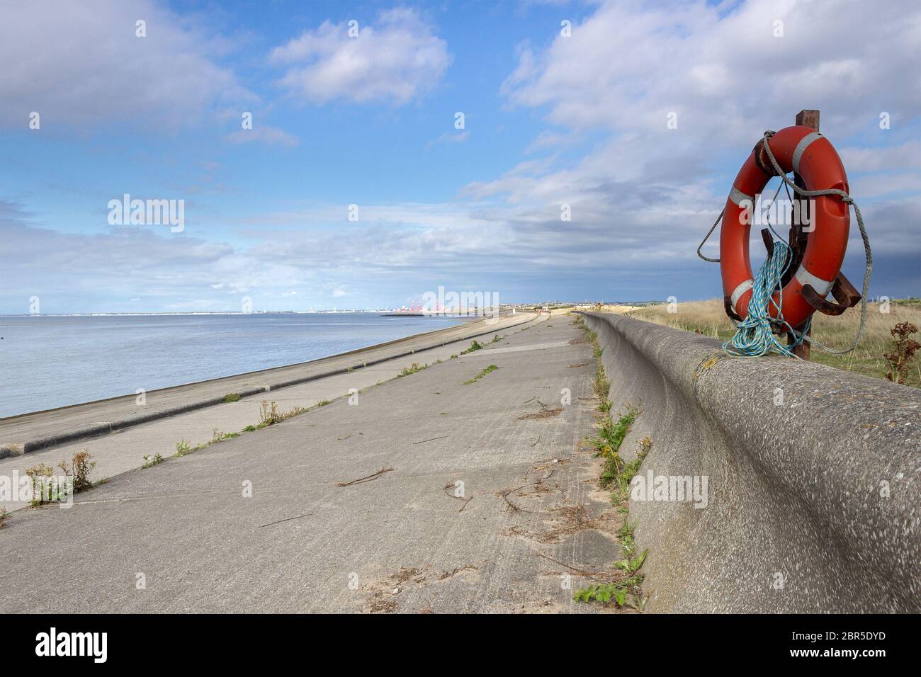 Punto Lifebuoy sulla fortificazione difensiva marina dell'argine di Wallasey. Guardando a nord lungo la costa verso Liverpool. Foto Stock