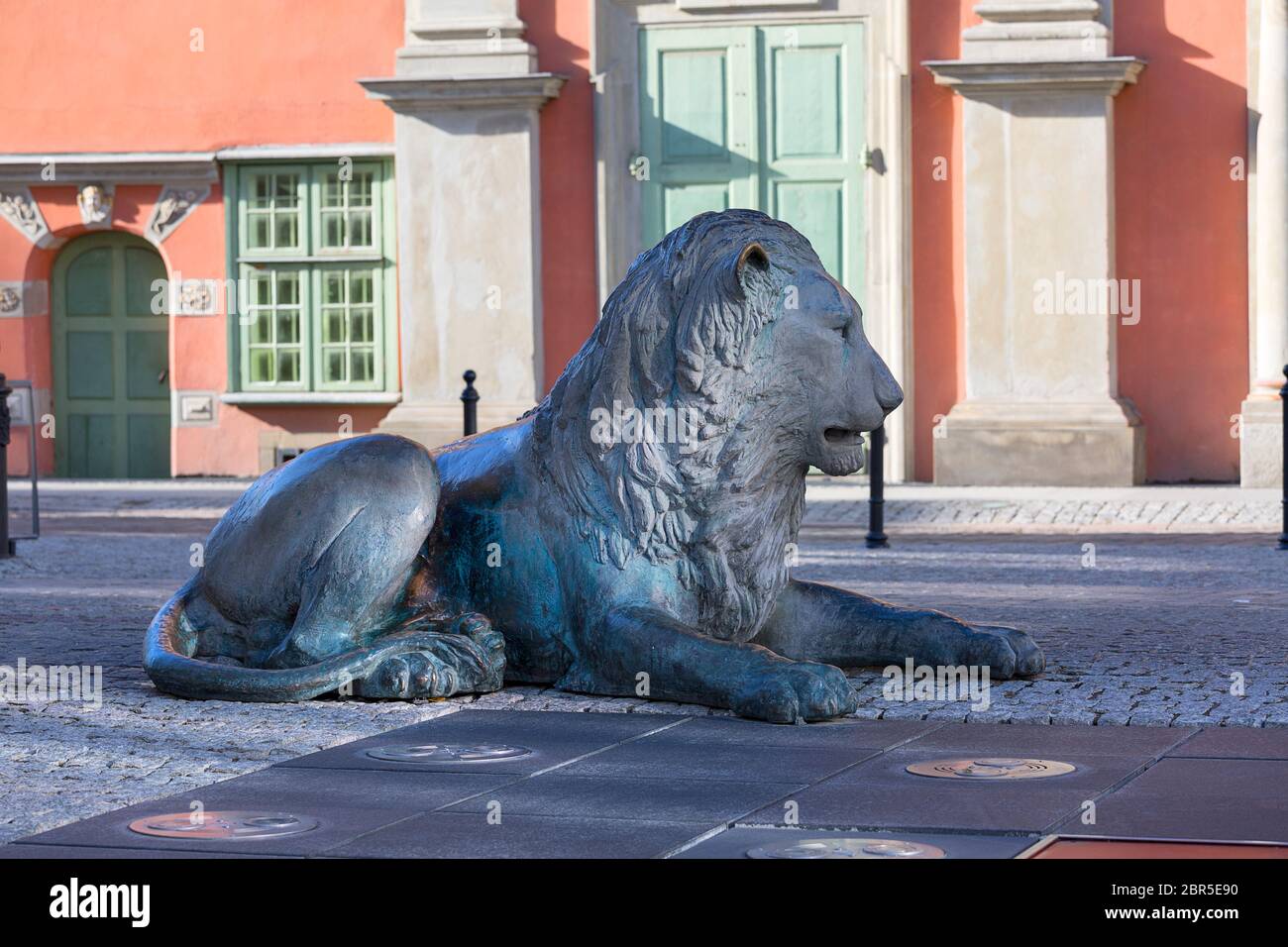 Fontana dei quattro quarti, scultura in bronzo di un leone che giace sulla strada, di fronte alla Cappella reale barocca, Danzica, Polonia Foto Stock