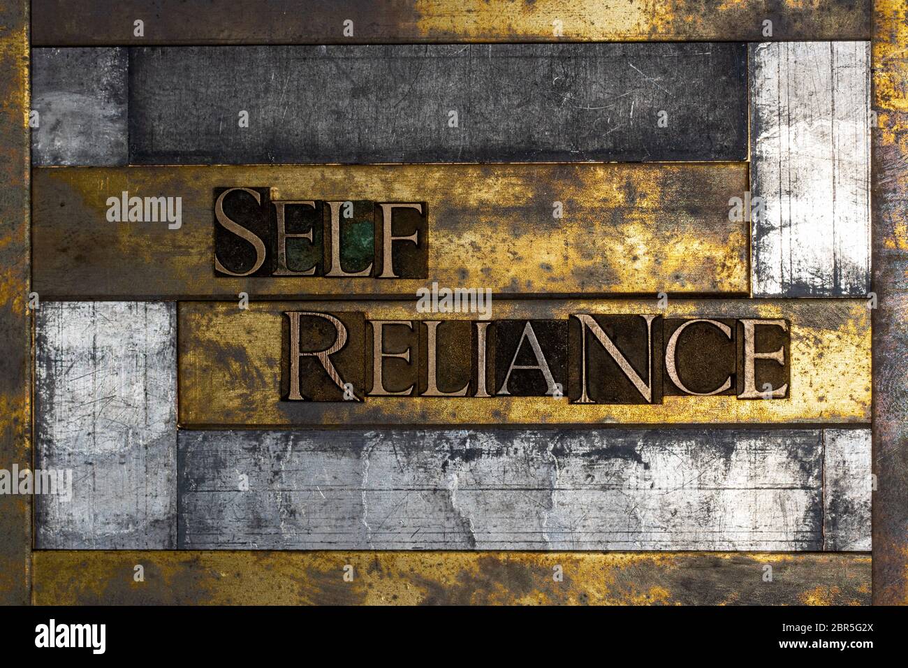 Foto di autentiche lettere di typeset che formano il testo di self Reliance su sfondo d'argento e oro testurizzato vintage Foto Stock