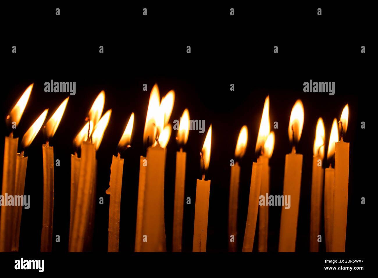Molti Natale candele accese di notte su sfondo nero. Candela set isolato in sfondo nero. Gruppo di candele accese nel buio con Foto Stock