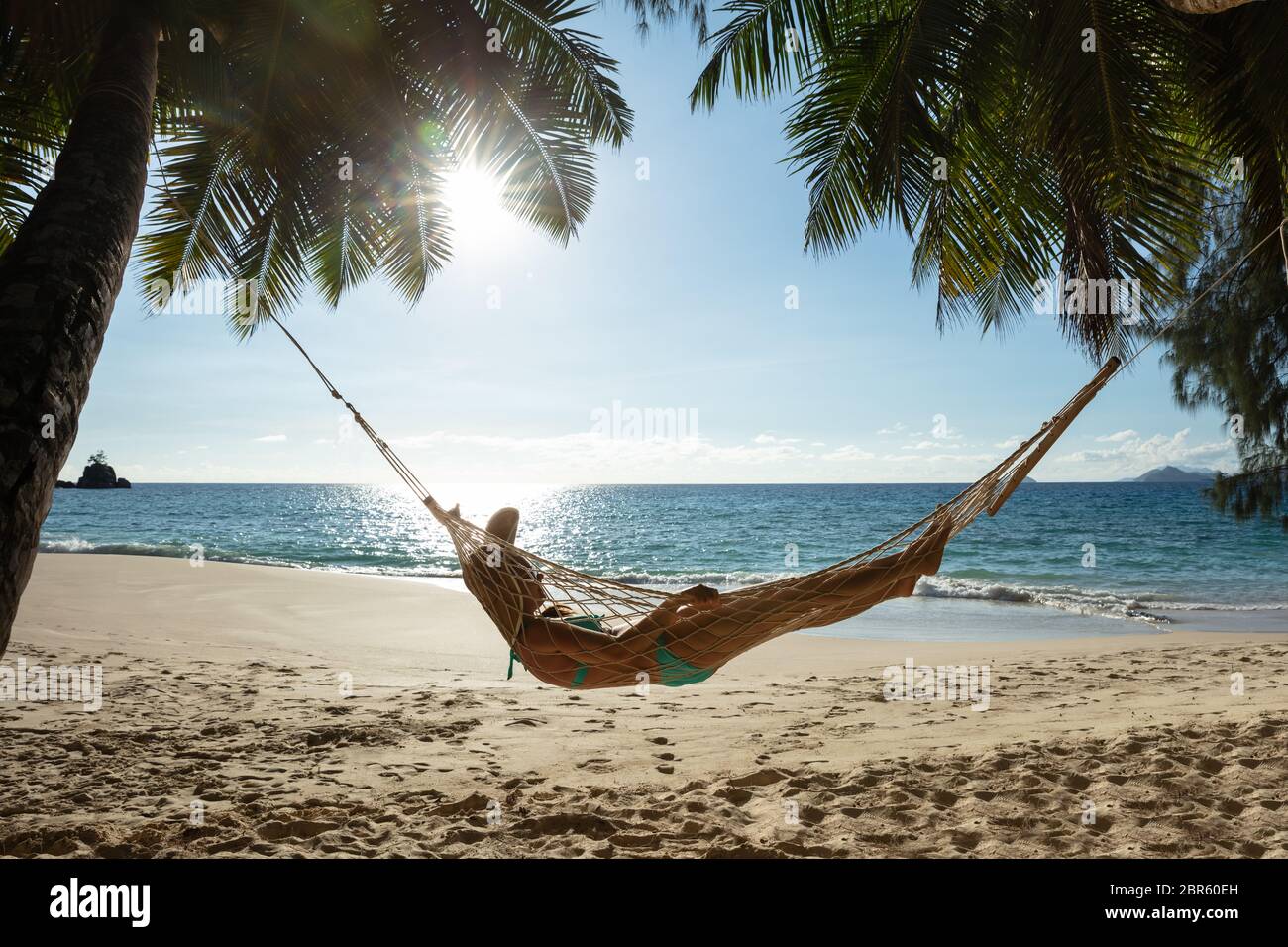 Donna sdraiata sull'amaca tra le palme di fronte al mare in spiaggia Foto  stock - Alamy