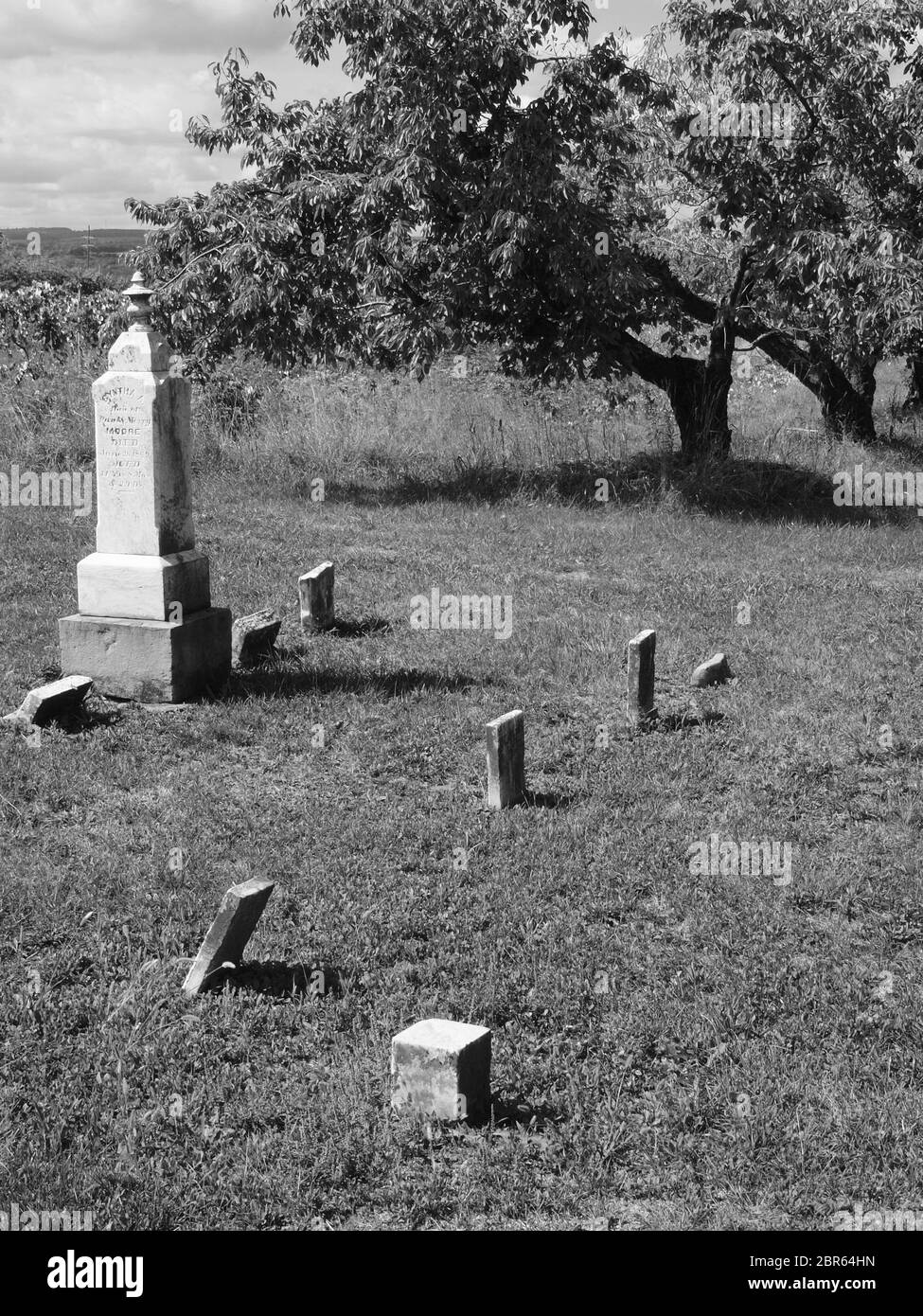 Antico cimitero in bianco e nero risalente al 1800. Mostrando negligenza e usura, alcune pietre sono sull'orlo di cadere. Foto Stock