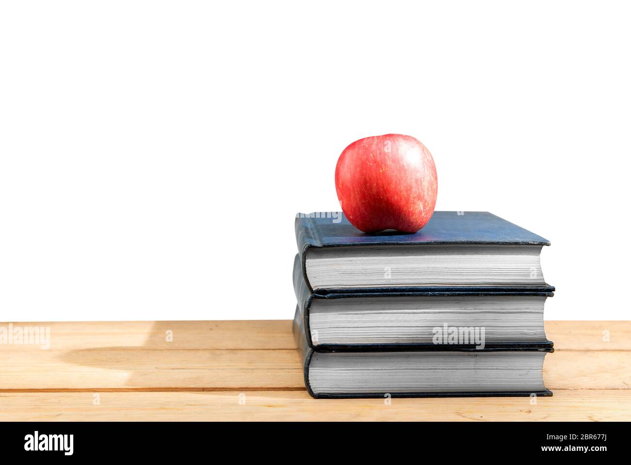 Pila di libri con Apple sul tavolo di legno isolato su sfondo bianco. Si torna a scuola concept Foto Stock