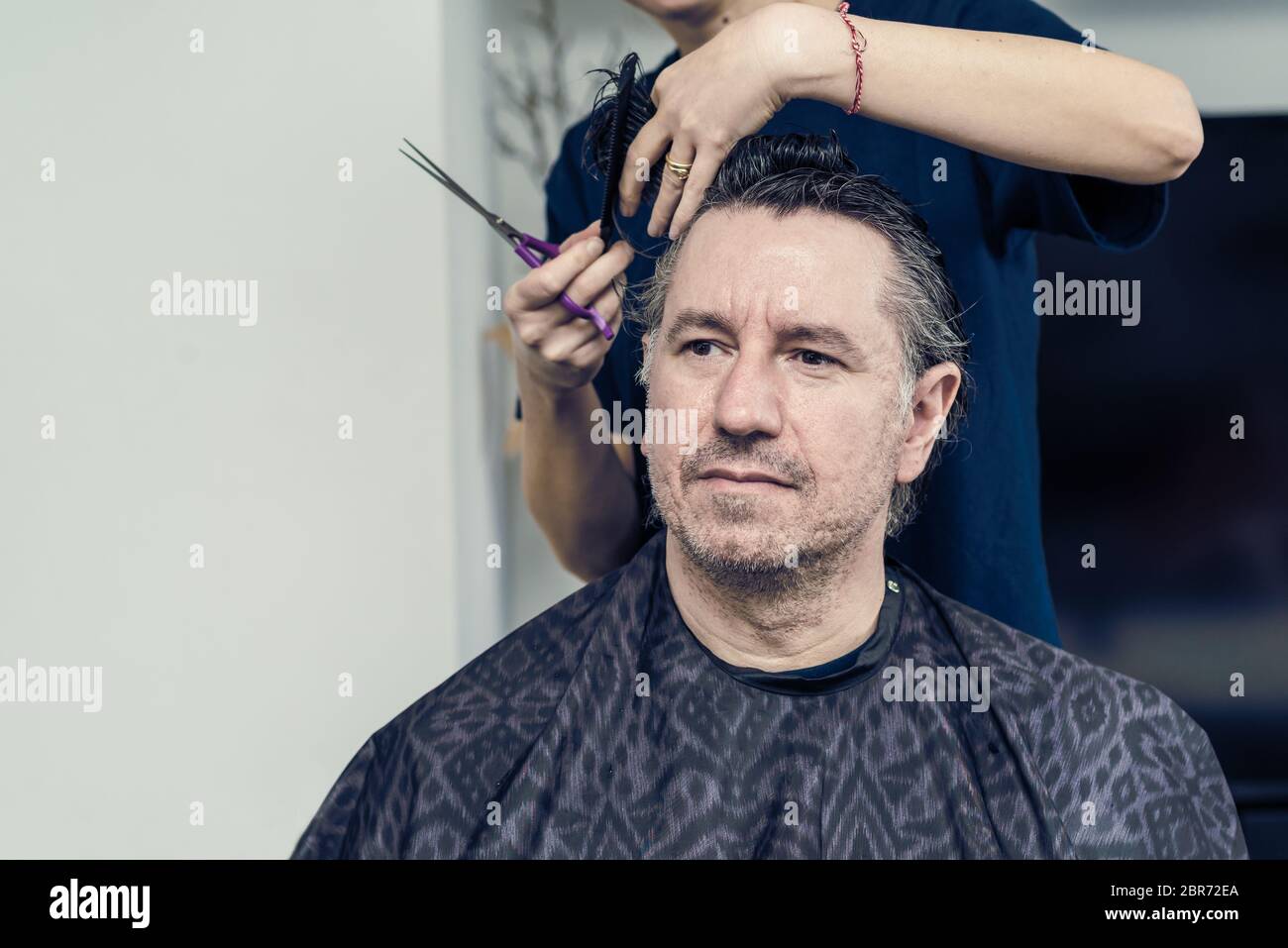 La moglie taglia i capelli sul marito a casa durante la quarantena in mezzo COVID-19 coronavirus pandemia Foto Stock