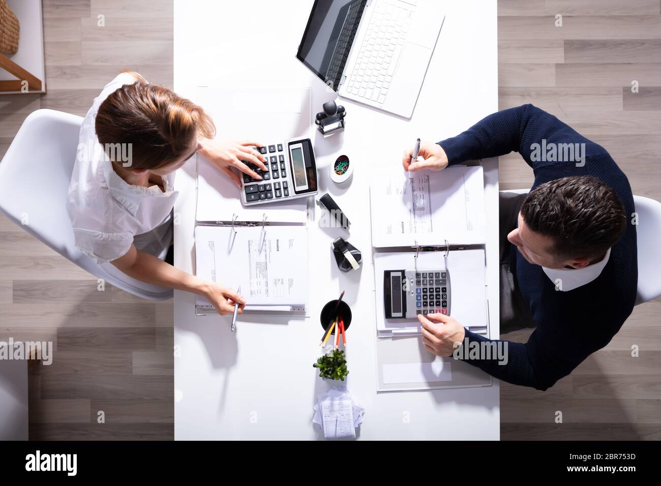 Alta Vista angolo di maschio e femmina imprenditori calcolo fattura con calcolatrice in ufficio Foto Stock