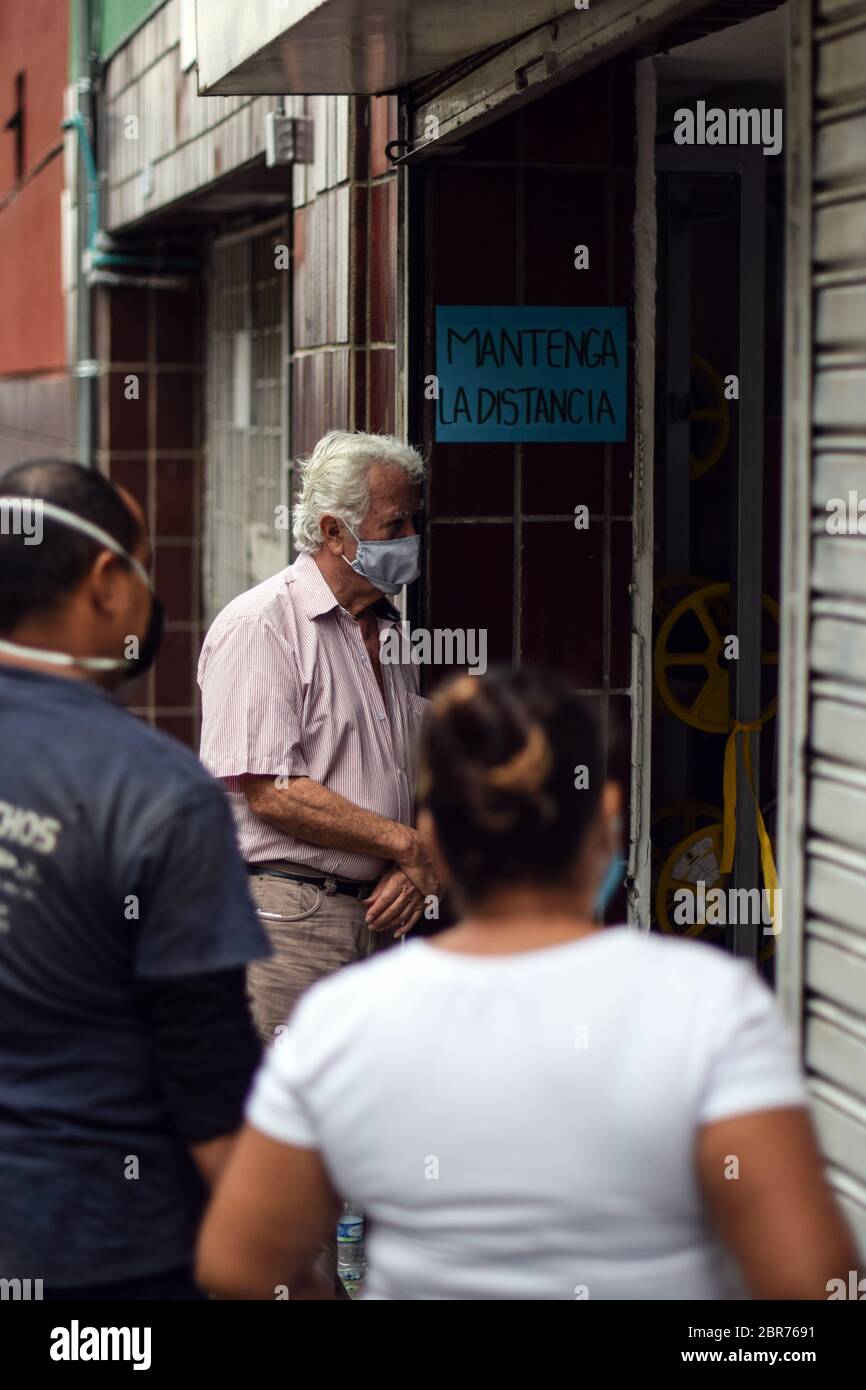 I clienti aspettano in coda fuori da un'azienda durante l'epidemia di Coronavirus in Colombia Foto Stock