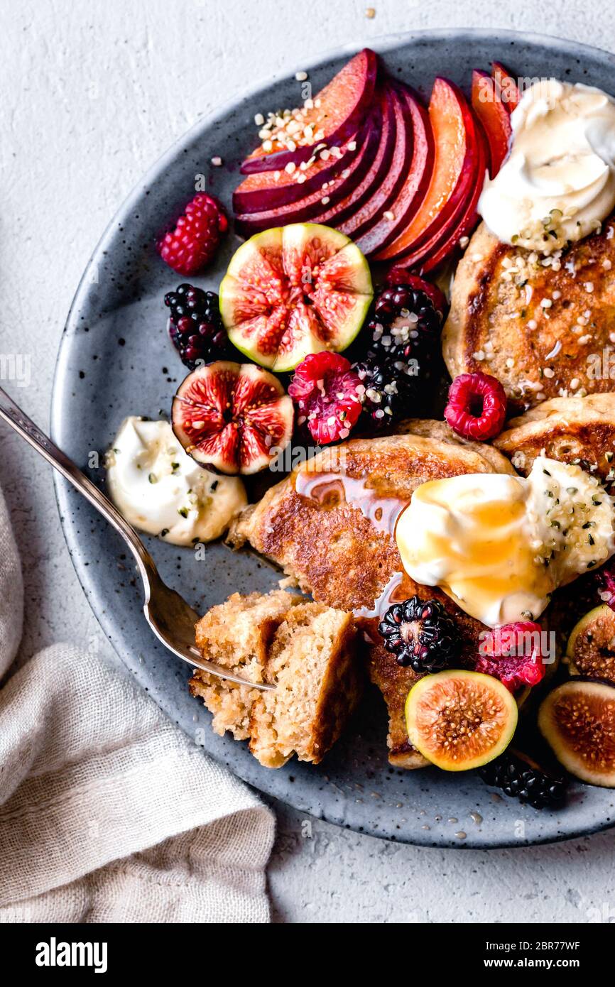 Vista in primo piano sui pancake serviti con yogurt, fichi, frutti di bosco e semi di canapa. Foto Stock