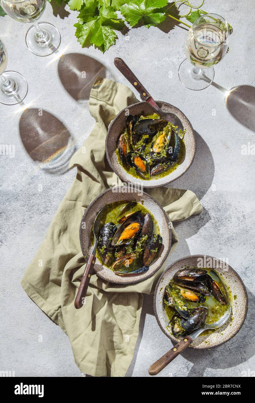 Cena in stile mediterraneo. Piatto-piatto di tavola con cozze in salsa verde e vino bianco, vista dall'alto. Foto Stock