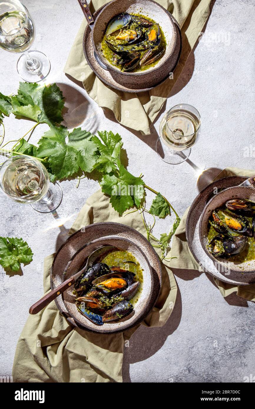 Cena in stile mediterraneo. Piatto-piatto di tavola con cozze in salsa verde e vino bianco, vista dall'alto. Foto Stock