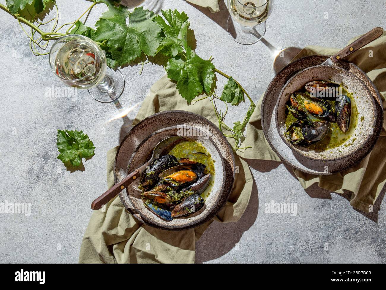 Cena in stile mediterraneo. Piatto-piatto di tavola con cozze in salsa verde e vino bianco, vista dall'alto. Foto Stock
