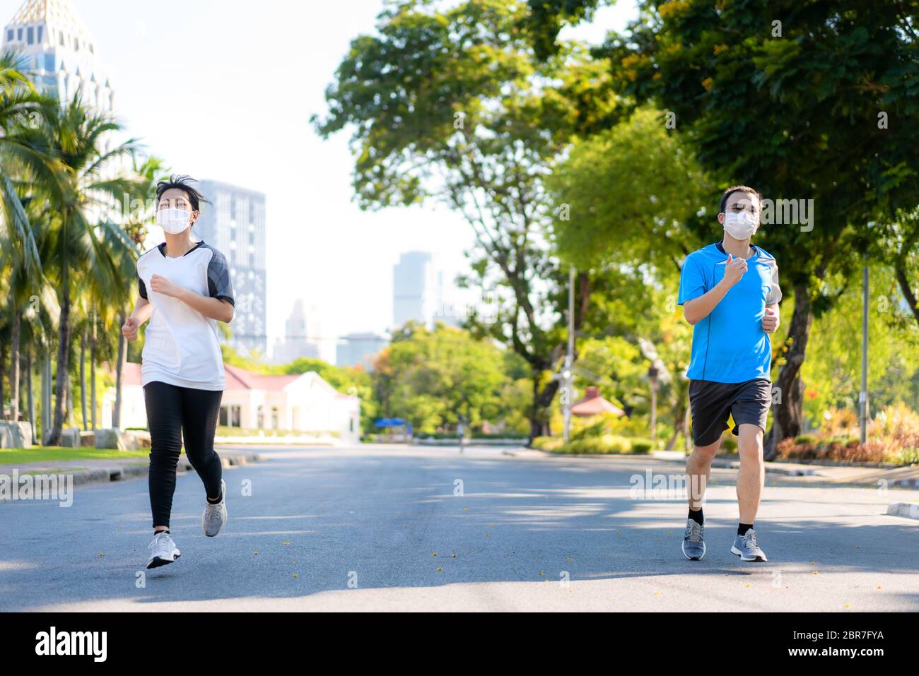 Giovane coppia asiatica donna e uomo sono jogging e exciseing all'aperto nel parco della città e indossando maschera protettiva sul viso per rimanere in forma durante Covid-19 pa Foto Stock