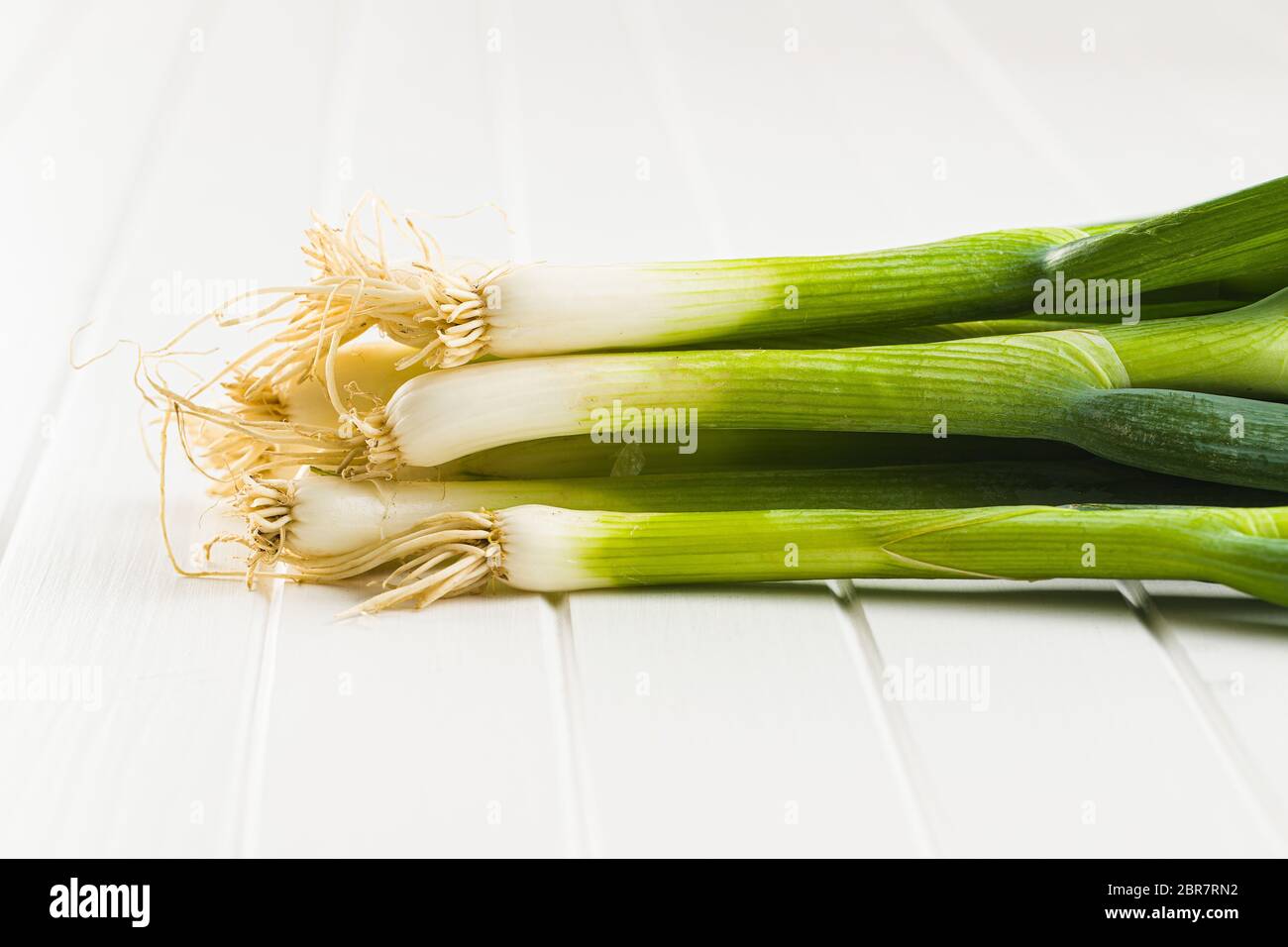 Il verde delle cipolline sul tavolo bianco. Foto Stock