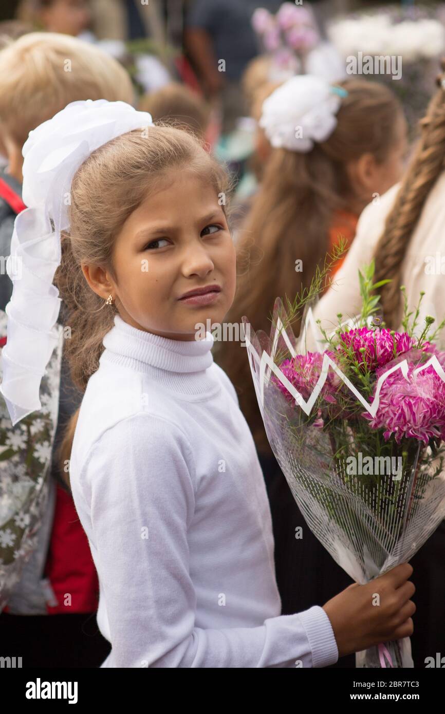 I bambini delle prime classi della scuola con un bouquet di fiori celebrano il loro primo giorno di scuola Foto Stock