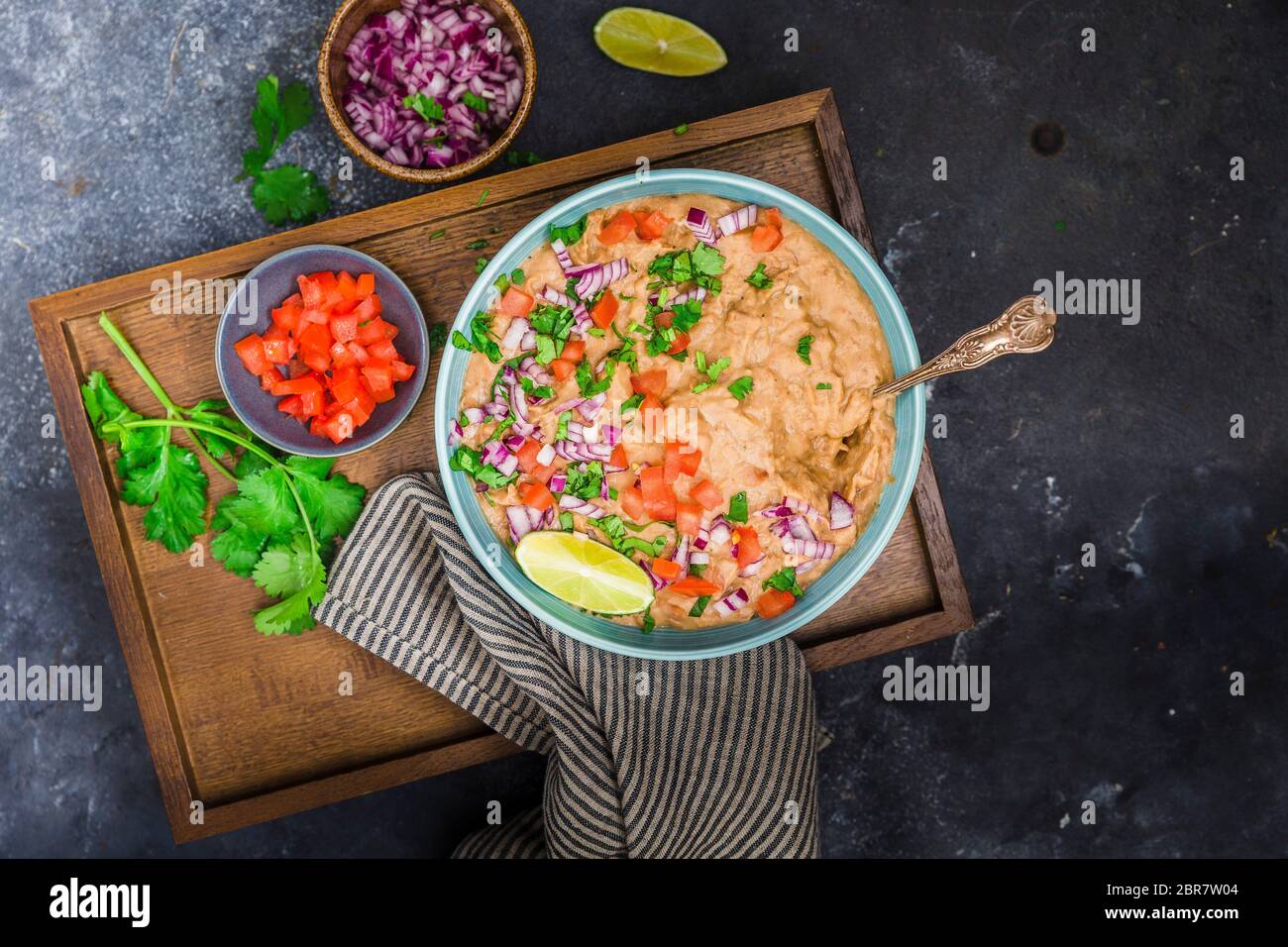 Fagioli fritti serviti con cipolla, pomodoro, lime e foglie di coriandolo Foto Stock