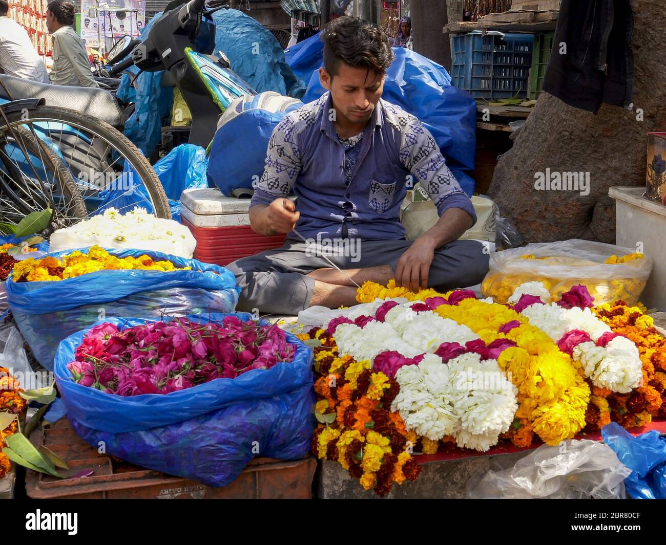 DELHI, INDIA - 14 MARZO 2019: Un lavoratore maschile fa una ghirlanda di fiori al mercato delle spezie di chandni chowk nella vecchia delhi, india Foto Stock