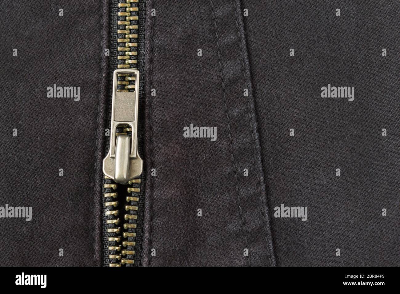 Aprire zip in ottone sul Jeans nero lo sfondo di texture. Aprire zip in ottone sul Jeans nero Texture di sfondo Design Abbigliamento Foto Stock