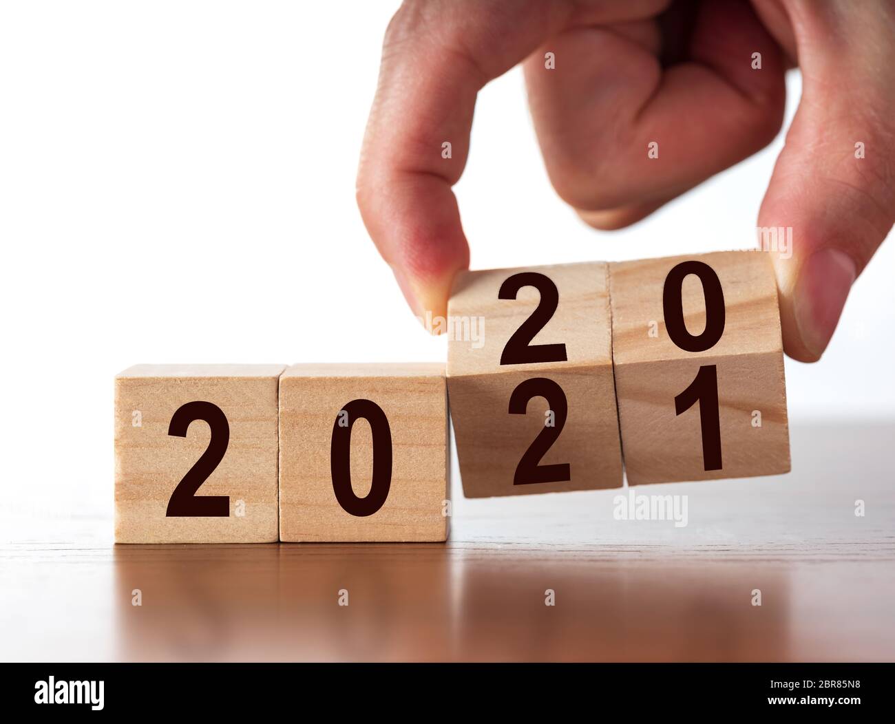 Concetto di nuovo anno dal 2020 al 2021. Cambio mano cubetti di legno su tavolo bianco. Foto Stock