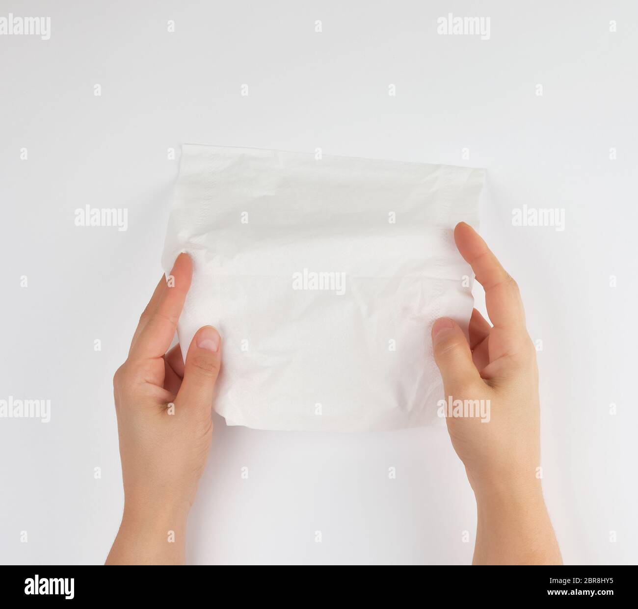 Tessuto per il viso in mani femminili su sfondo bianco, vista dall'alto Foto Stock