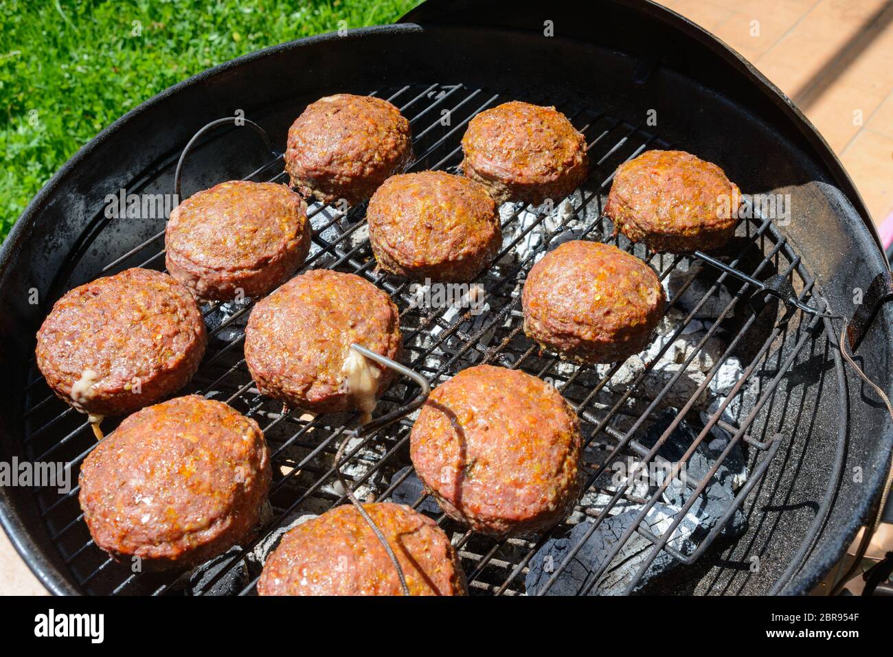 Grandi carni bovine e il formaggio hamburger la cottura all'interno del barbecue Foto Stock