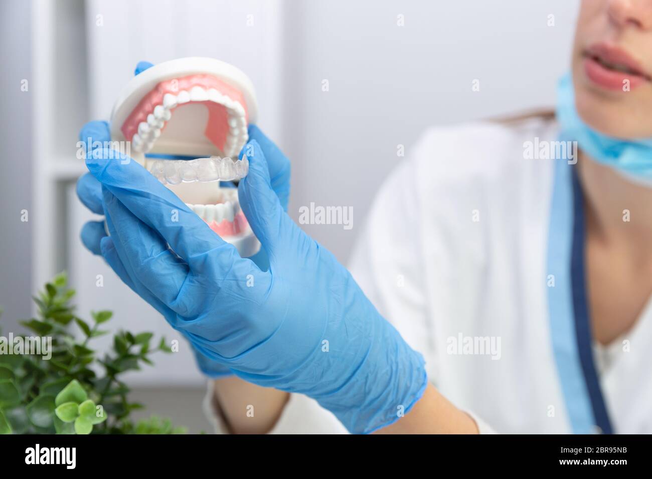 Dentista femmina che mantiene i denti modello e silicone ortodontico trainer. Invisibile allineatore di bretelle. Mobile apparecchio ortodontico per la correzione dentale Foto Stock