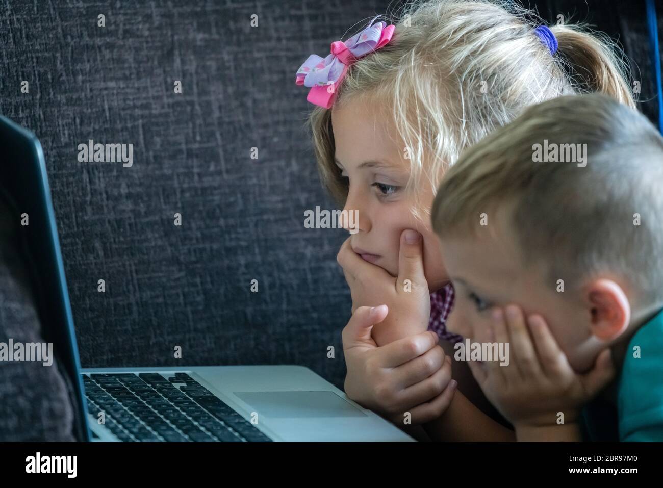 Figlioli a guardare cartoon su un computer portatile mentre sdraiato sul divano in un salotto di casa Foto Stock