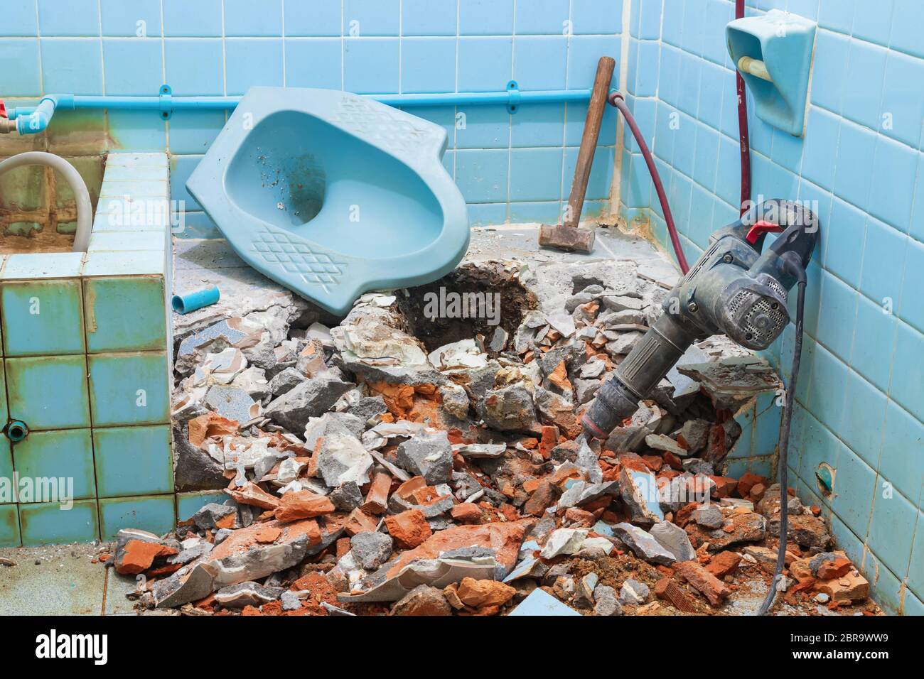 Riparazione wc casa vecchia bagno interno e martello pneumatico con grande martello in acciaio Foto Stock