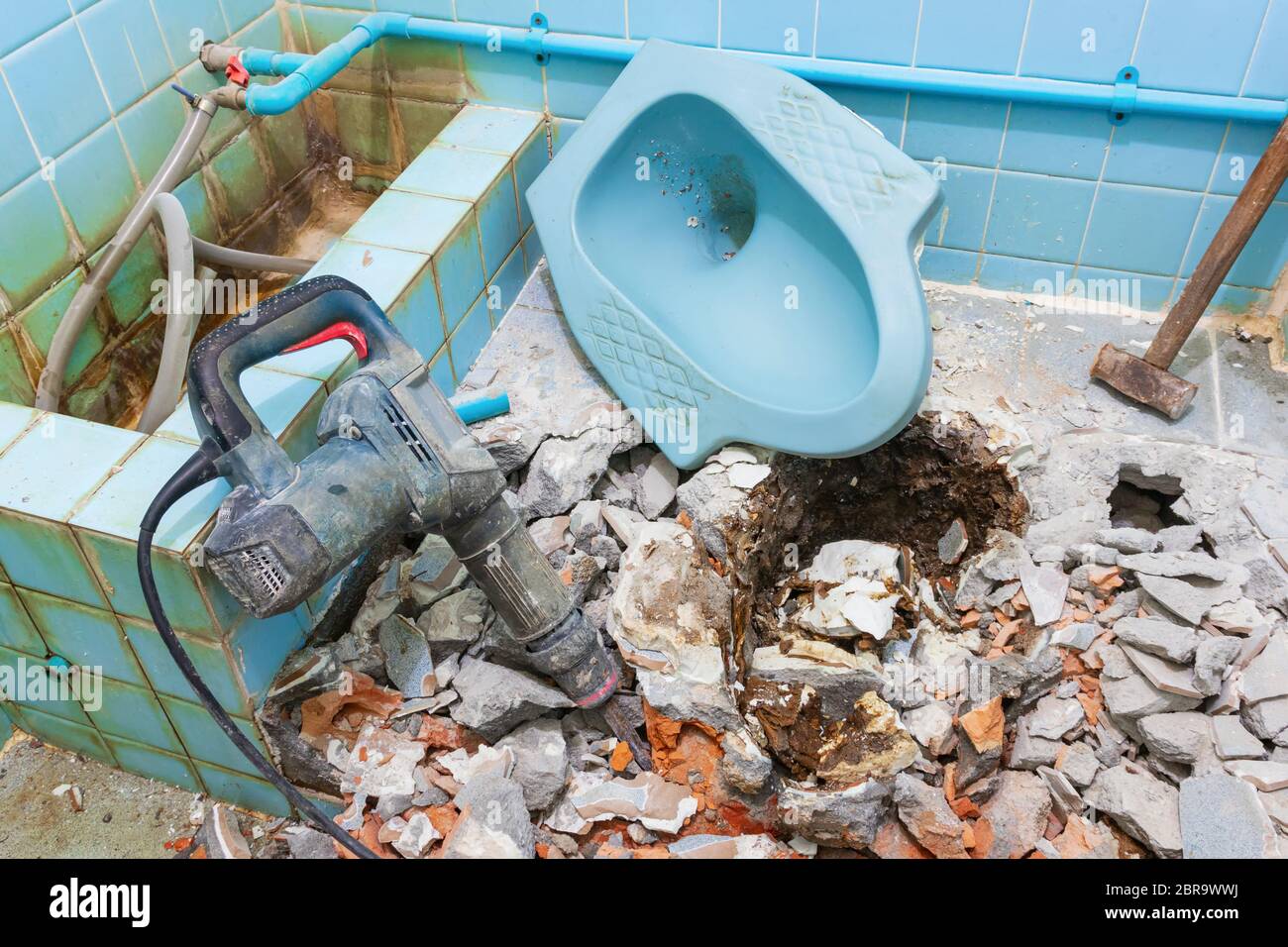 Riparazione wc casa vecchia bagno interno e martello pneumatico con grande martello in acciaio Foto Stock