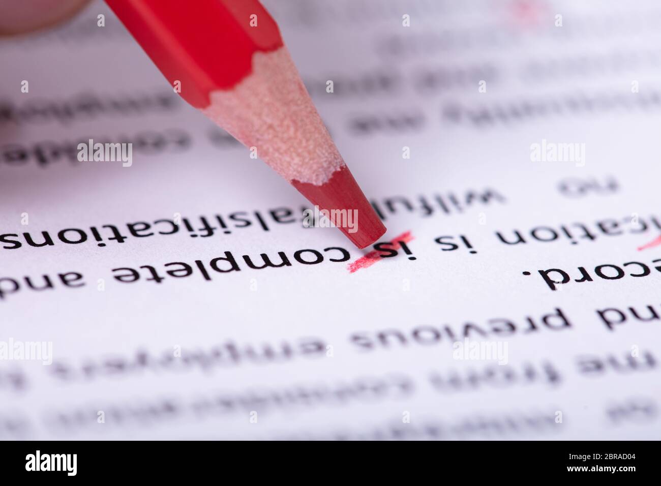 Close-up di matita rossa marcatura errore durante il controllo ortografico del testo sul documento di carta Foto Stock