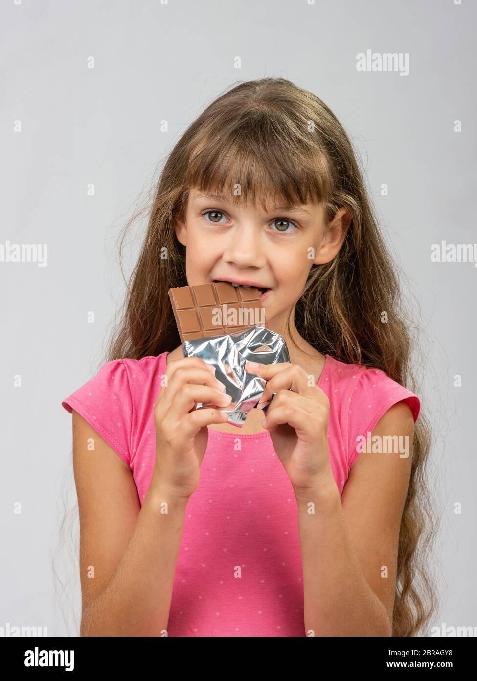 Teen girl morsi barra di cioccolato e guardava a sinistra Foto Stock