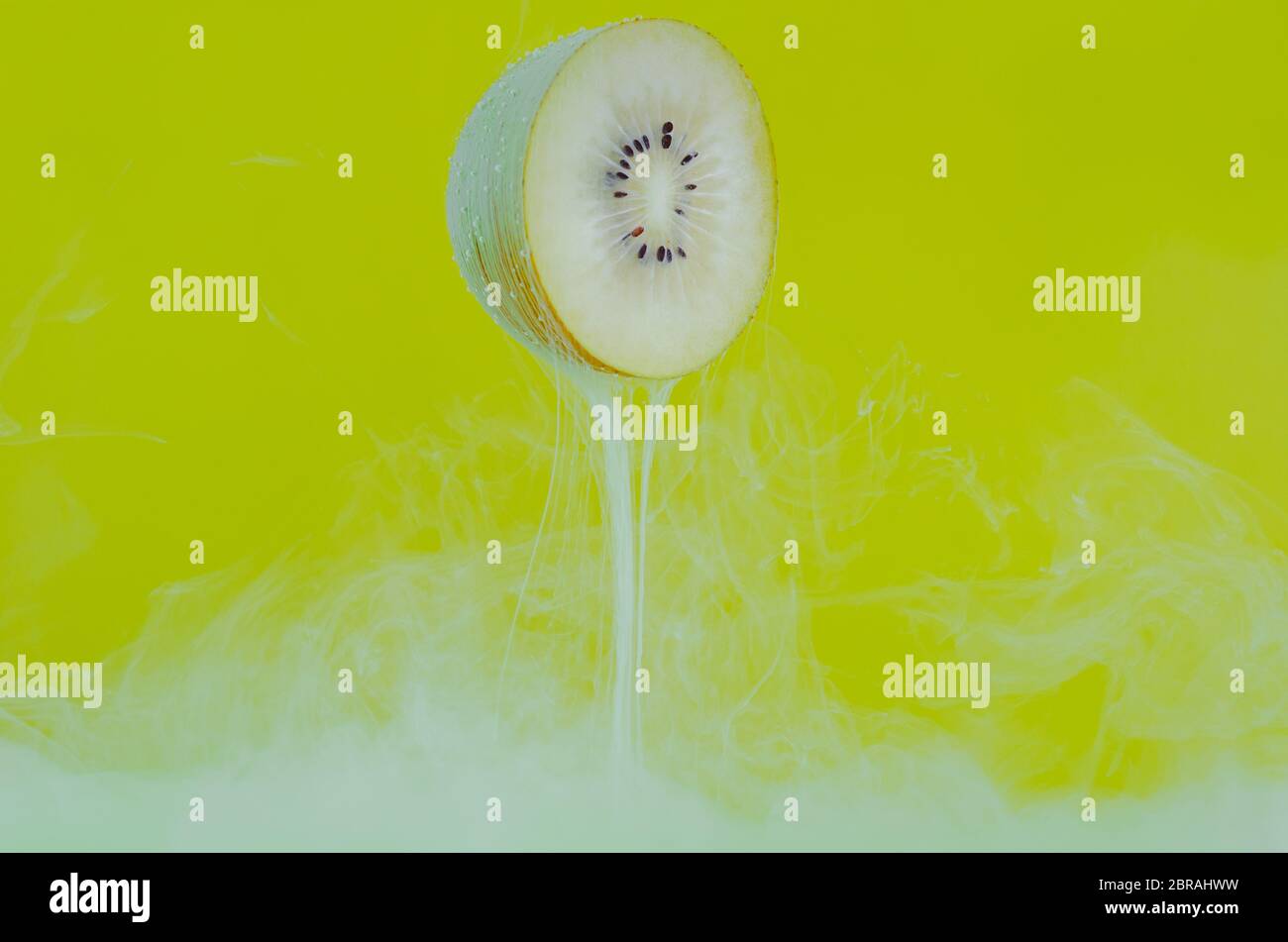 Fuoco offuscato di sciogliere il colore verde del manifesto in acqua con la fetta di frutta kiwi su sfondo giallo per il concetto di estate, astratto e di fondo. Foto Stock