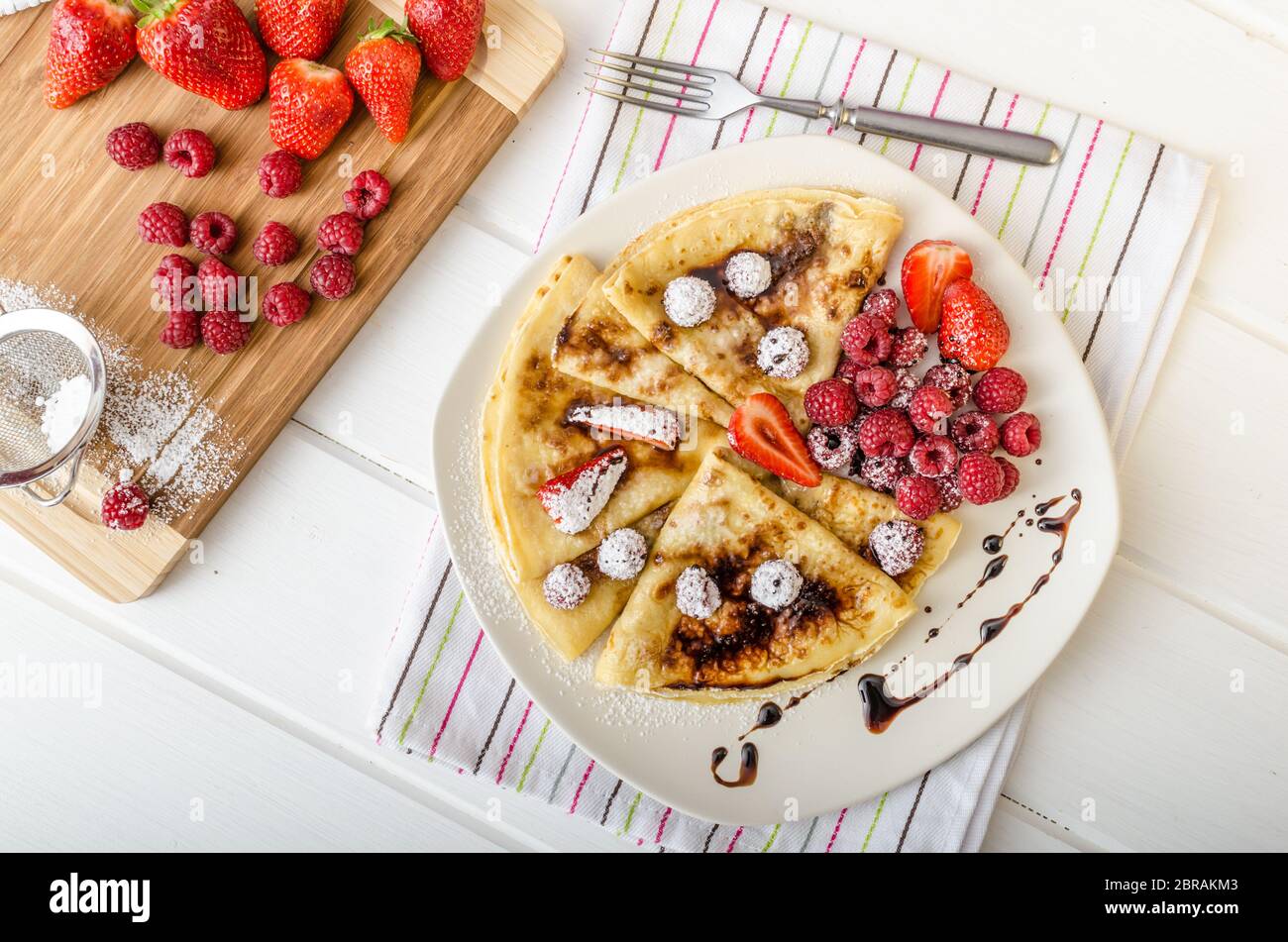 Frittelle fatte in casa con riduzione di balsamico e frutta fresca, fragole e lamponi Foto Stock