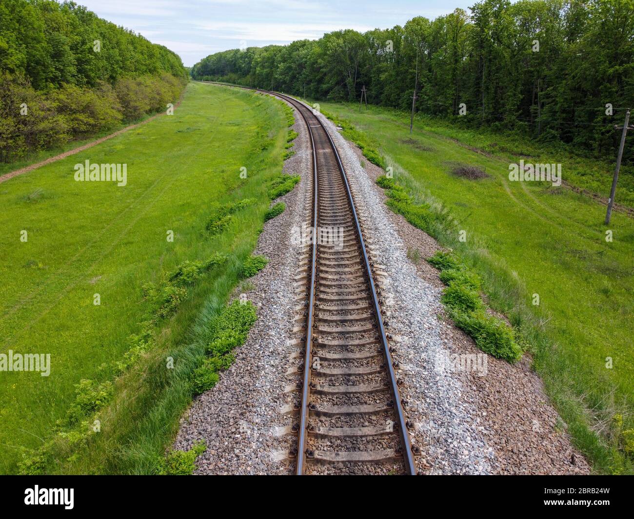Binari ferroviari, una strada per il cibo che passa attraverso la natura bella, erba verde, alberi e tempo di primavera. Foto Stock